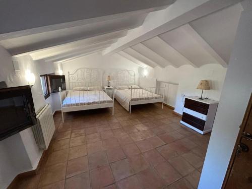 an attic room with two beds and a tv at Cortijo Burruelo in Algodonales