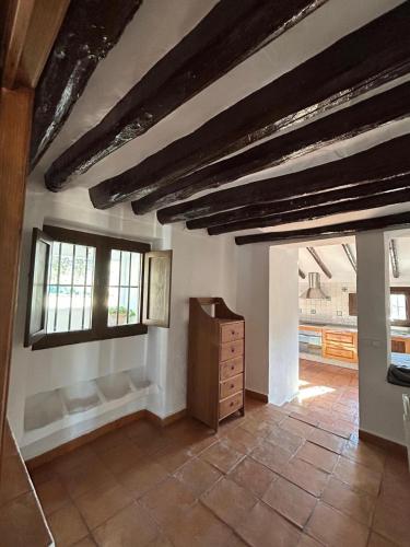 a room with wooden ceilings and a dresser and windows at Cortijo Burruelo in Algodonales