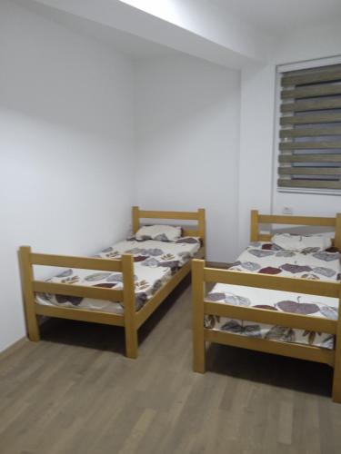 two beds in a room with white walls and wooden floors at Eva apartment in Štip