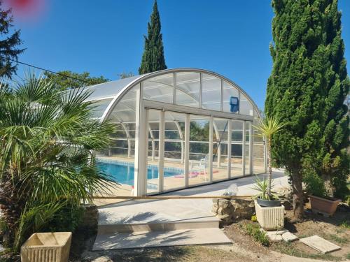 une maison en verre avec une piscine dans un jardin dans l'établissement La Magnanerie en Provence Bolléne, à Bollène