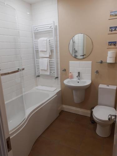 a bathroom with a tub and a sink and a toilet at Snooze Apartments in Newcastle