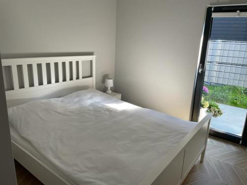 ein weißes Bett in einem Schlafzimmer mit einem Fenster in der Unterkunft Apartament Ustrońska Jodełka z Sauną-Nadrzeczna in Ustroń
