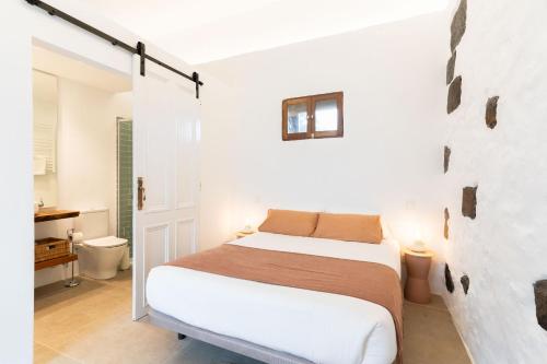 a white bedroom with a bed and a bathroom at Studio Canario with patio - Casa del Indiano in La Orotava
