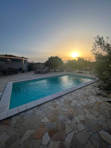 a swimming pool with a sunset in the background at Il Tramonto in Giba