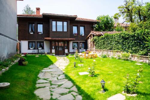 una casa con un patio verde delante de ella en Къща ЕТНО, en Koprivshtitsa