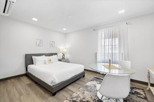 um quarto branco com uma cama e uma mesa de vidro em Sunset Inn-South Miami em South Miami
