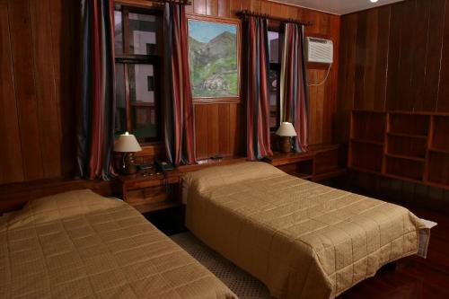 a bedroom with two beds and a window at Hotel Du Lac Macaé in Macaé