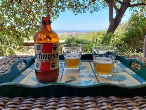 uma garrafa de cerveja e dois copos numa mesa em Villetta in zona panoramica, immersa nel verde della macchia mediterranea em Villasimius