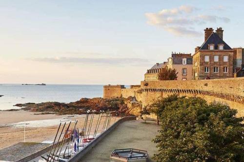 a building on a cliff next to a beach at La Perle Marine in Le Vivier-sur-Mer