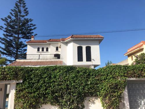 a white house with a hedge in front of it at Villa Hanaa in Mohammedia