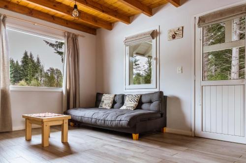 a living room with a couch and two windows at BOG Carileufu in Villa La Angostura