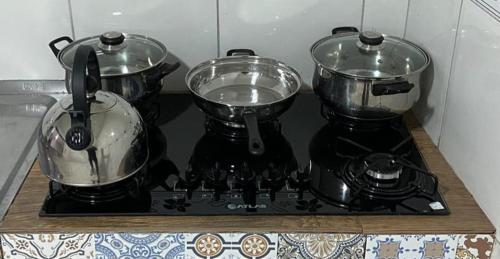 three pots and pans sitting on a stove top at Casa de Wagner in Triunfo