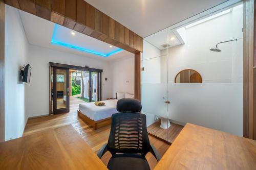 a bedroom with a bed and a desk with a chair at ZenDen Wellness Guesthouse in Canggu