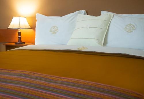 a bedroom with a bed with white pillows and a lamp at Los Alamos in Caraz