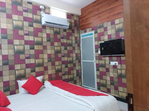 a bedroom with a bed with red pillows and a tv at Parvati home stay in Ujjain