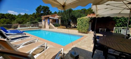 a swimming pool with chairs and an umbrella at Au petit bonheur in Carnoules