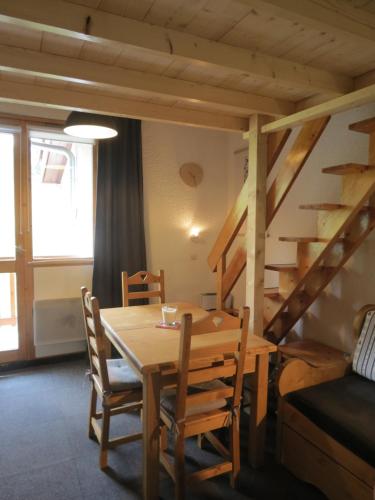 une pièce avec une table, des chaises et un escalier dans l'établissement Duplex plein sud_skis aux pieds_Plagne villages, à La Plagne Tarentaise