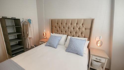 a bedroom with a white bed with two blue pillows at Kaneel Suiker in Paarl