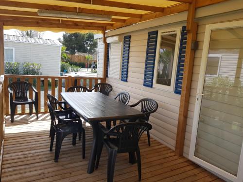 une terrasse en bois avec une table et des chaises dessus dans l'établissement mobil home 8 personnes les sables du midi, à Sérignan