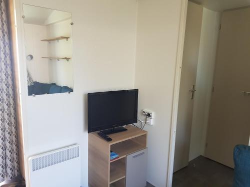 un salon avec une télévision et une petite table avec une télévision dans l'établissement mobil home 8 personnes les sables du midi, à Sérignan