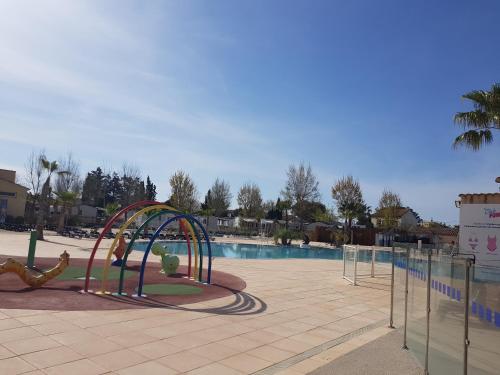 une aire de jeux en face d'une piscine dans l'établissement mobil home 8 personnes les sables du midi, à Sérignan