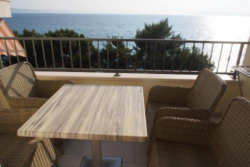 a wooden table and chairs on a balcony with the ocean at Vila Snježana Tučepi in Tučepi