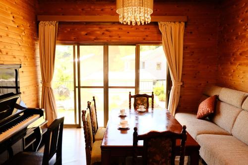 a dining room with a table and a piano at Forest-inn Kasama in Kasama