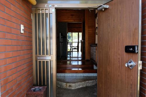 an open door to a hallway with a brick wall at Forest-inn Kasama in Kasama