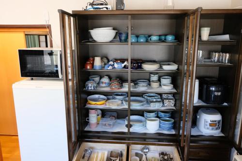 a cabinet filled with cups and plates and bowls at Forest-inn Kasama in Kasama