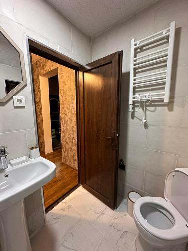 a bathroom with a toilet and a sink and a door at B&B House in Mestia