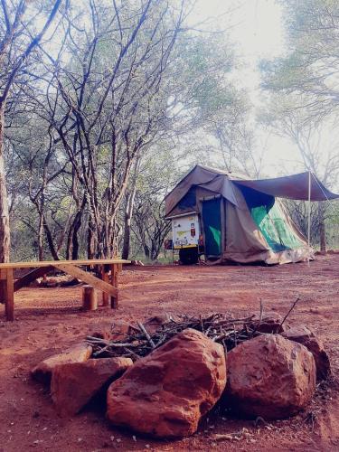 a tent in a field with rocks and trees at Impala trailor tent in Thabazimbi