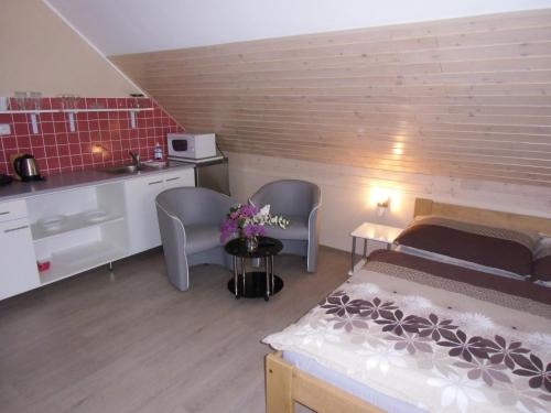 a bedroom with a bed and two chairs and a kitchen at Penzion Sarton in Lukov