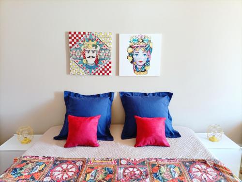 a bedroom with a bed with red pillows and two paintings at Villemar in Isola delle Femmine