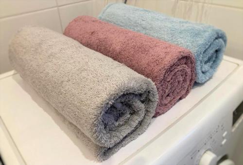 drie handdoeken zittend op een plank in een badkamer bij Biały Dom - 2 Bedrooms in Katowice