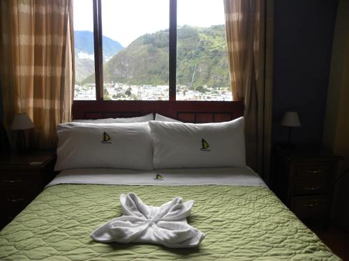 a bed with a white towel on it with a window at Hosteria Llanovientos in Baños