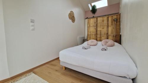 een slaapkamer met een bed met 2 roze kussens erop bij LogeYou in Chartres-de-Bretagne