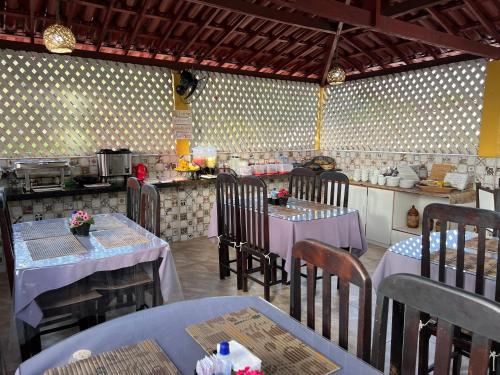 a restaurant with tables and chairs and a kitchen at Pousada Lua Rosa in Piranhas