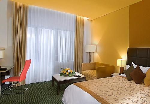 una camera d'albergo con un letto, una scrivania e una sedia di Golden Flower by KAGUM Hotels a Bandung