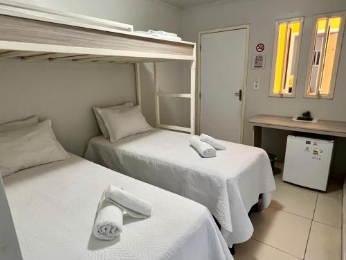 Pousada Lua Rosa في ببرانا: سريرين في غرفة الفندق ذات شراشف بيضاء
