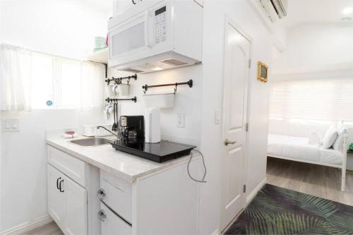 a white kitchen with a sink and a microwave at Studio Bungalow in the Heart of Normal Heights in San Diego