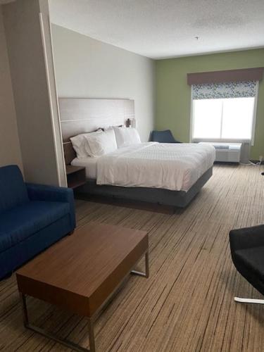 a hotel room with a bed and a blue chair at Holiday Inn Express & Suites - Enterprise by IHG in Enterprise