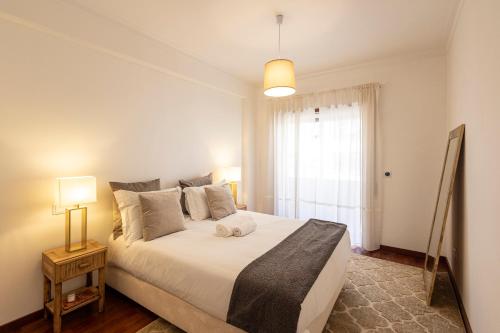 a bedroom with a large white bed and a window at Braga 3BR Wonder by LovelyStay in Braga