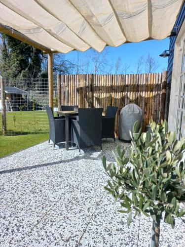a patio with a table and chairs and a fence at B&B Ouddorps Huisje in Ouddorp