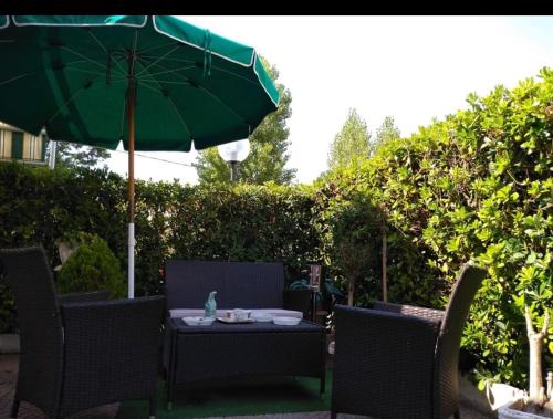 an outdoor table with a green umbrella and chairs at L'angolo della felicità in Marina di Montenero