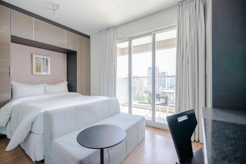 um quarto com uma cama branca e uma grande janela em Tabas - VN Quatá em São Paulo