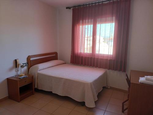 a small bedroom with a bed and a window at Hostal Fontdemora in Mora la Nueva