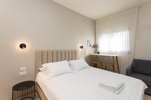 a bedroom with a large white bed and a chair at Carmel Studio By Carmel Boutique in Haifa