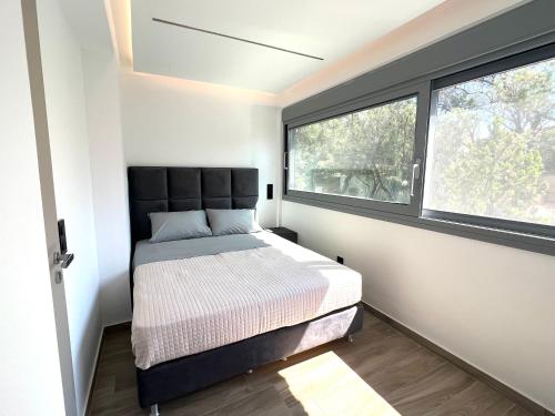 a small bedroom with a bed and two windows at Sounio - Waterfront Luxury Spa Villa Pounta Zeza 170 sqm on Private Beach in Sounio