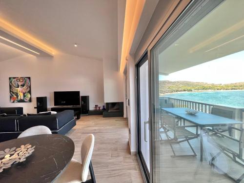 a living room with a table and a view of the ocean at Sounio - Waterfront Luxury Spa Villa Pounta Zeza 170 sqm on Private Beach in Sounio
