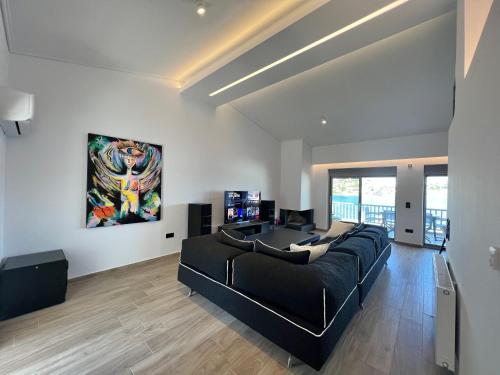 a living room with a black couch and a painting on the wall at Sounio - Waterfront Luxury Spa Villa Pounta Zeza 170 sqm on Private Beach in Sounio